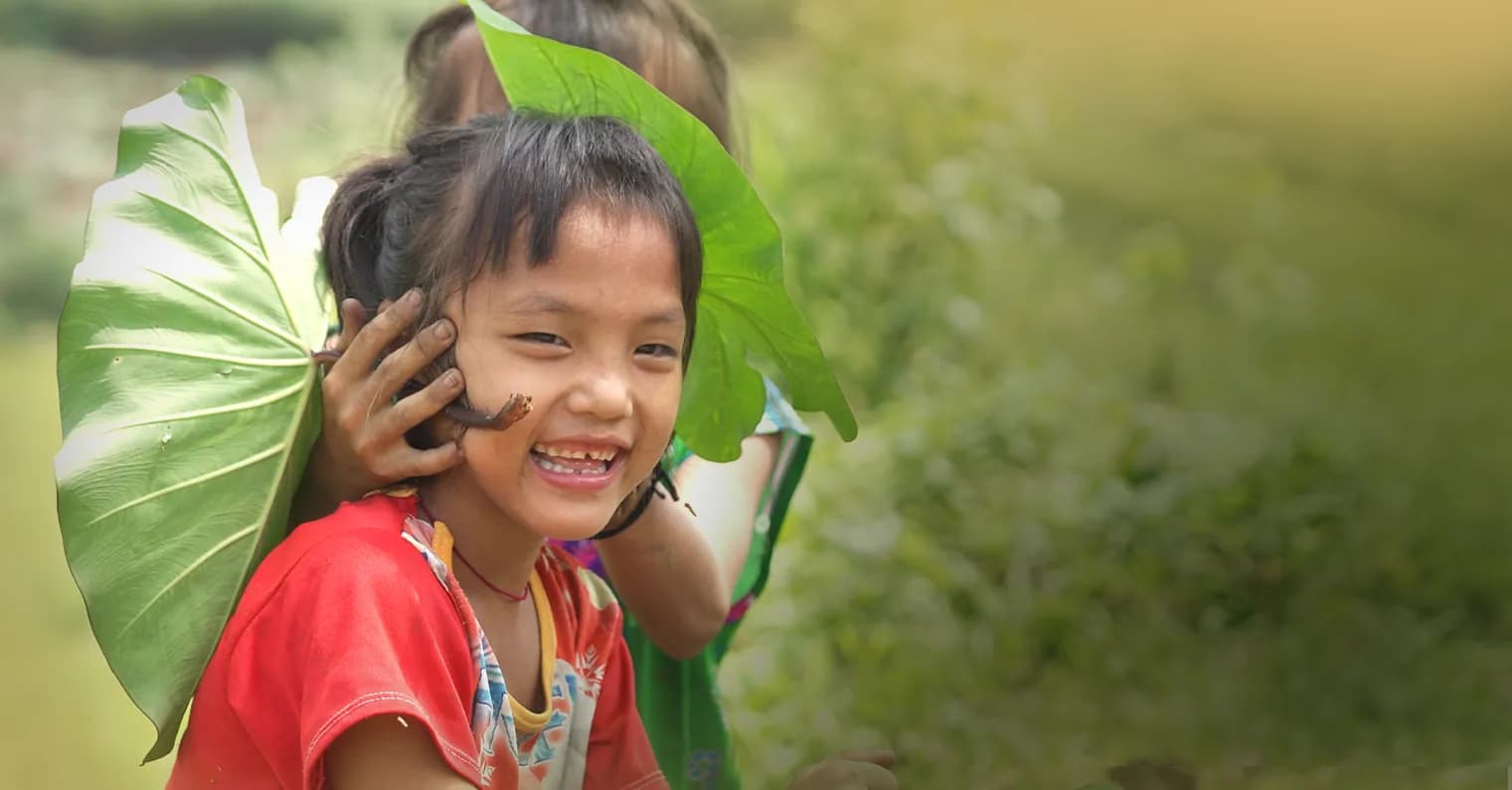 Em nhỏ vùng cao cười rạng rỡ bên tàu lá